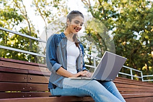 Amazing young beautiful woman sitting outdoors using laptop computer.
