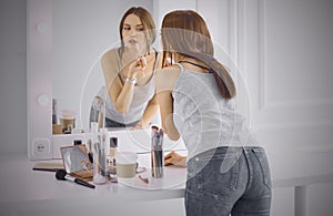 Amazing young woman doing her makeup in front of mirror. Portra