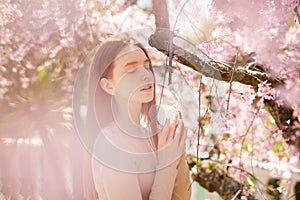 Amazing young woman posing with cream bottle cosmetics in Blooming tree at spring