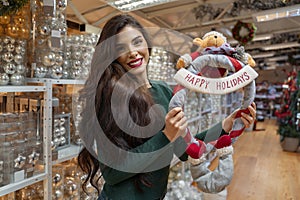 Amazingly beautiful, cheerful woman  holding  Happy holidays plush toy ornament