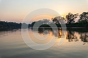 Amazon rainforest sunset during a boat trip with a reflection of the trees in the water. Puerto Francisco de Orellana. Ecuador.