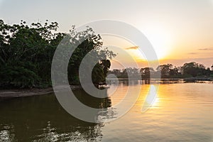 Amazon rainforest sunset during a boat trip with a reflection of the trees in the water. Puerto Francisco de Orellana. Ecuador.