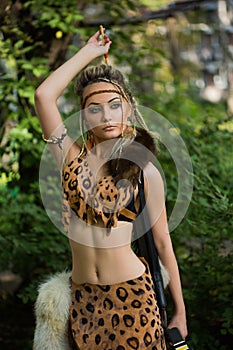 Amazon woman posing with bow in green forest