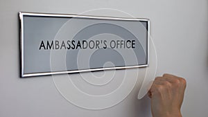 Ambassador office door, hand knocking closeup, visa consultation service, travel