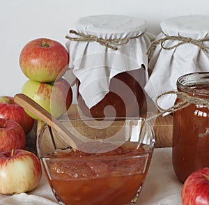 Amber apple jam in a salad bowl on a wooden table with jars of jam in the background. Season for making jam for future use