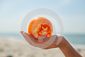 Amber ball holding hand close up baltic sea background