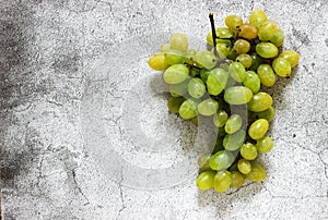 Amber bunch of grapes on a gray concrete background.