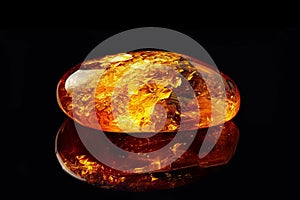 Amber Crystal Isolated, Golden Amber Pebble on Black