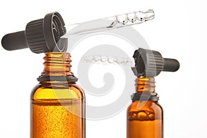 Two pipettes with serum are on brown open bottles necks. photo