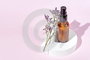 Amber glass bottle with pomp lid on the white podiums. Pink background. Container mockup with face cream or serum. Showcase for