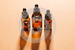 Amber glass cosmetic bottles with a dropper on a beige background. Natural cosmetics concept, natural essential oil and skin care