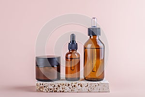 Amber glass jar mockup with cream and two amber glass dropper bottles mockup on pink background