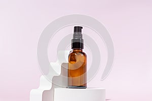 Amber glass pomp bottle with black lid on a podium on light pink background. Skincare products , natural cosmetic. Beauty concept