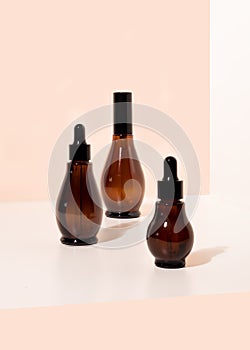 Amber glass spray and dropper bottles with cosmetic on light bathroom table.