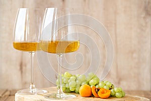 Amber or white wine with fruit. Poured glass with wine surrounded by grapes, peaches and pears