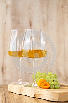Amber or white wine with fruit. Poured glass with wine surrounded by grapes, peaches and pears