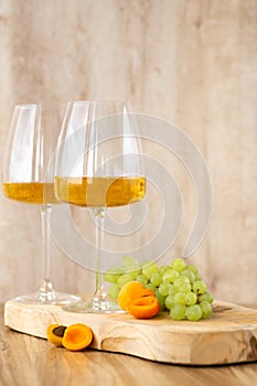 Amber or white wine with fruit. Poured glass with wine surrounded by grapes, peaches and pears