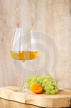 Amber or white wine with fruit. Poured glass with wine surrounded by grapes, peaches and pears