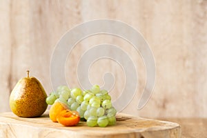 Amber or white wine with fruit. Poured glass with wine surrounded by grapes, peaches and pears