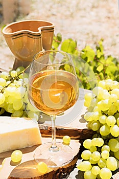Amber wine in glasses on the nature: still life with cheese, grapes and wine in a rustic style. Georgian national wine or italian