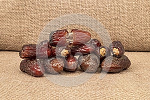 Ambera and Medjool dates isolated on the burlap background.