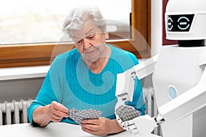 Ambient assisted living service robot is playing a card game with a senior adult woman