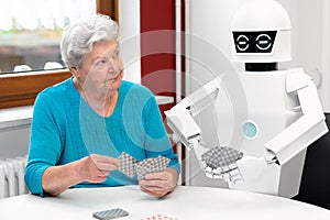 Ambient assisted living service robot is playing a card game with a senior adult woman photo