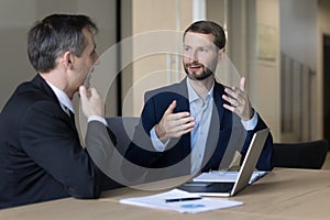 Ambitious business man talking to boss, elder colleague at workplace