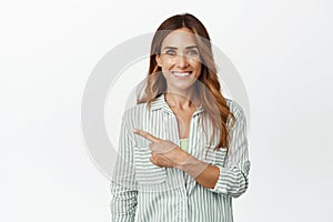 Ambitious business woman smiling, pointing finger left at company logo, banner or sale promotion, standing happy and