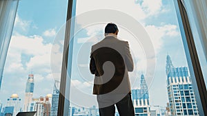 Ambitious businessman standing in ornamented office on cityscappe background