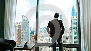 Ambitious businessman standing in ornamented office on cityscappe background