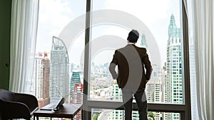 Ambitious businessman standing in ornamented office on cityscappe background