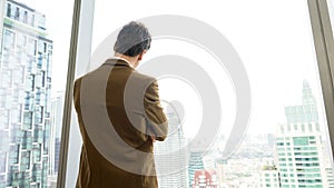 Ambitious businessman standing in ornamented office on cityscappe background