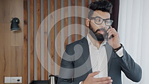 Ambitious Middle Eastern businessman making mobile call from hotel room