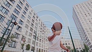 Ambitious strong guy doing stunts and tricks with basket ball on townscape background. Dribbling, spinning, rotation of