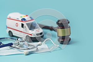 Ambulance car and brown gavel stethoscope and on a blue background. symbol photo for bungling and medical error