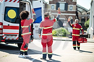 Ambulance doctors in the red uniforms greeting each other outdoors
