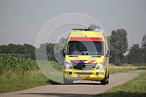 An ambulance is driving through the countryside