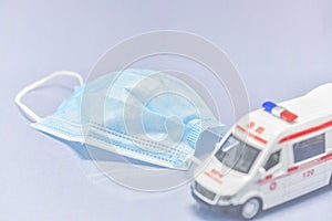 Ambulance model with medical mask on white background