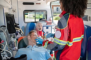 Ambulance personnel preparing a man for oxygen therapy