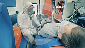 Ambulance worker measures patient`s pressure in a car. Coronavirus epidemic, covid-19 pandemic, virus disease concept.