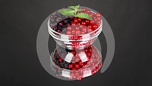 Amelanchier and red currant in a glass plate on black mirror. Loop motion. Side view. Rotation 360.