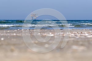 Ameland,Netherlands April 20,2021-NAM, Oil rig, offshore platform with beach, sand and surf. Natural gas extraction in