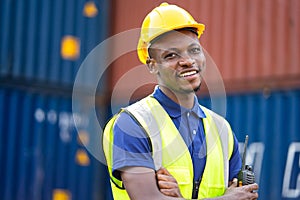 American African engineer or factory worker man smailing at Container cargo harbor to loading containers. African dock male staff