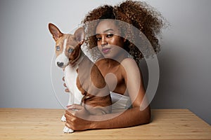 American african female with afro hair hugging her puppy basenji dog. Love between dog and owner. On white background