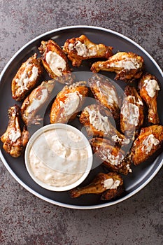 American Alabama White Sauce Chicken Wings closeup in the plate. Vertical top view