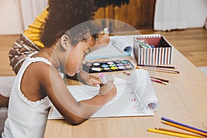 American Black preschool daughter kids doing homework learning education with her sister living together at home