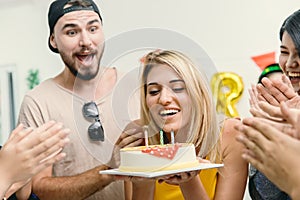 American blond beautiful girl blowing the birthday cake in the party with friends clap her birthday celebration song
