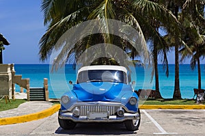 American blue Buick Eight classic car parked under palms on the beach in Varadero Cuba -Serie Cuba Reportage