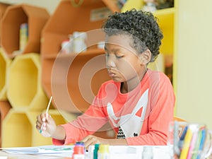 American boy make home wore drawing color pencils in kindergarten classroom, preschool library and kid education concept.